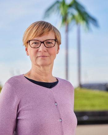 Eine Frau steht vor künstlichen Palmen