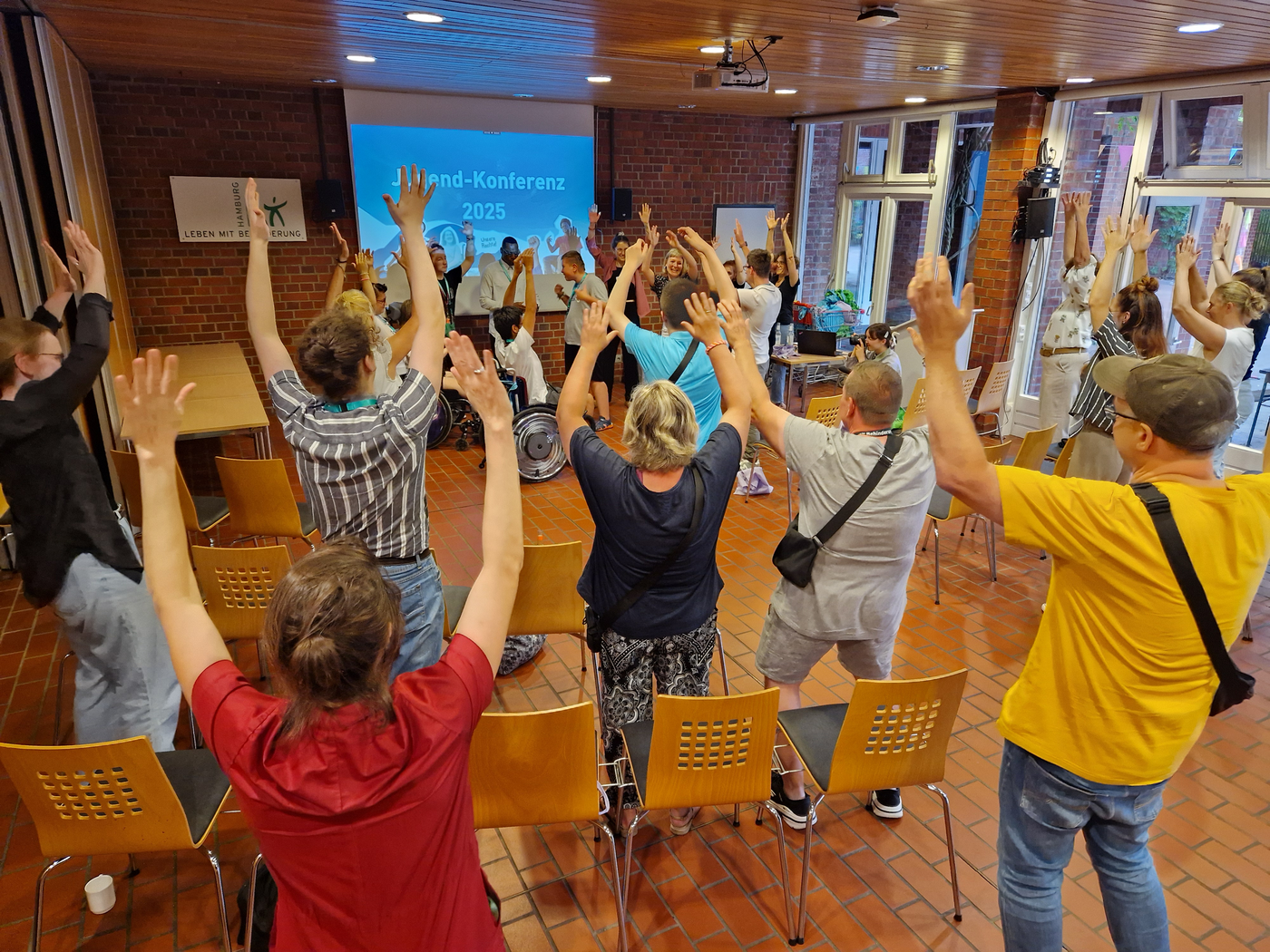 Teilnehmer*innen und Gäste der Jugendkonferenz machen mit beim Tanzen und strecken die Hände in die Höhe