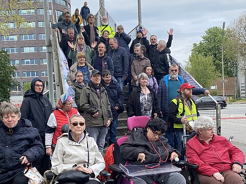 Menschen vor und auf einer Brücke. Darunter Rollstuhlfahrer*innen.