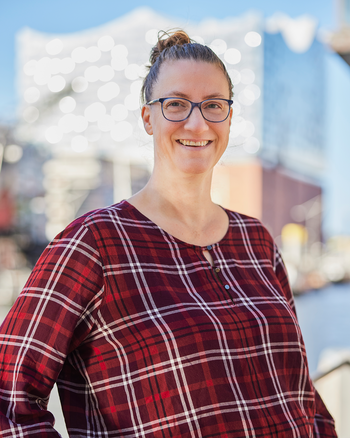 Eine Frau steht vor der Elbphilharmonie und lacht