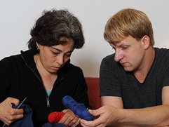 Zwei Personen sitzen nebeneinander, halten bunte Wollknäuel