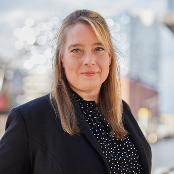 Eine Frau steht vor der Elbphilharmonie und lächelt.