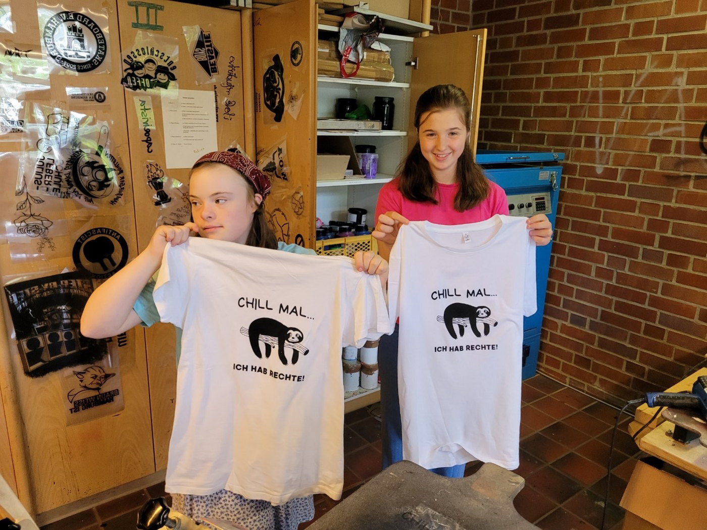 Workshop Wir machen Druck: zwei jugendliche Teilnehmerinnen präsentieren ihre bedruckten T-Shirts mit der Botschaft Wir haben Rechte
